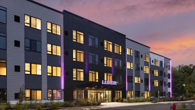 Westrum Corporate Modern Luxor Montgomeryville apartments with purple accent lights, sunset views, parking, and a landscaped entryway await you in Montgomeryville.